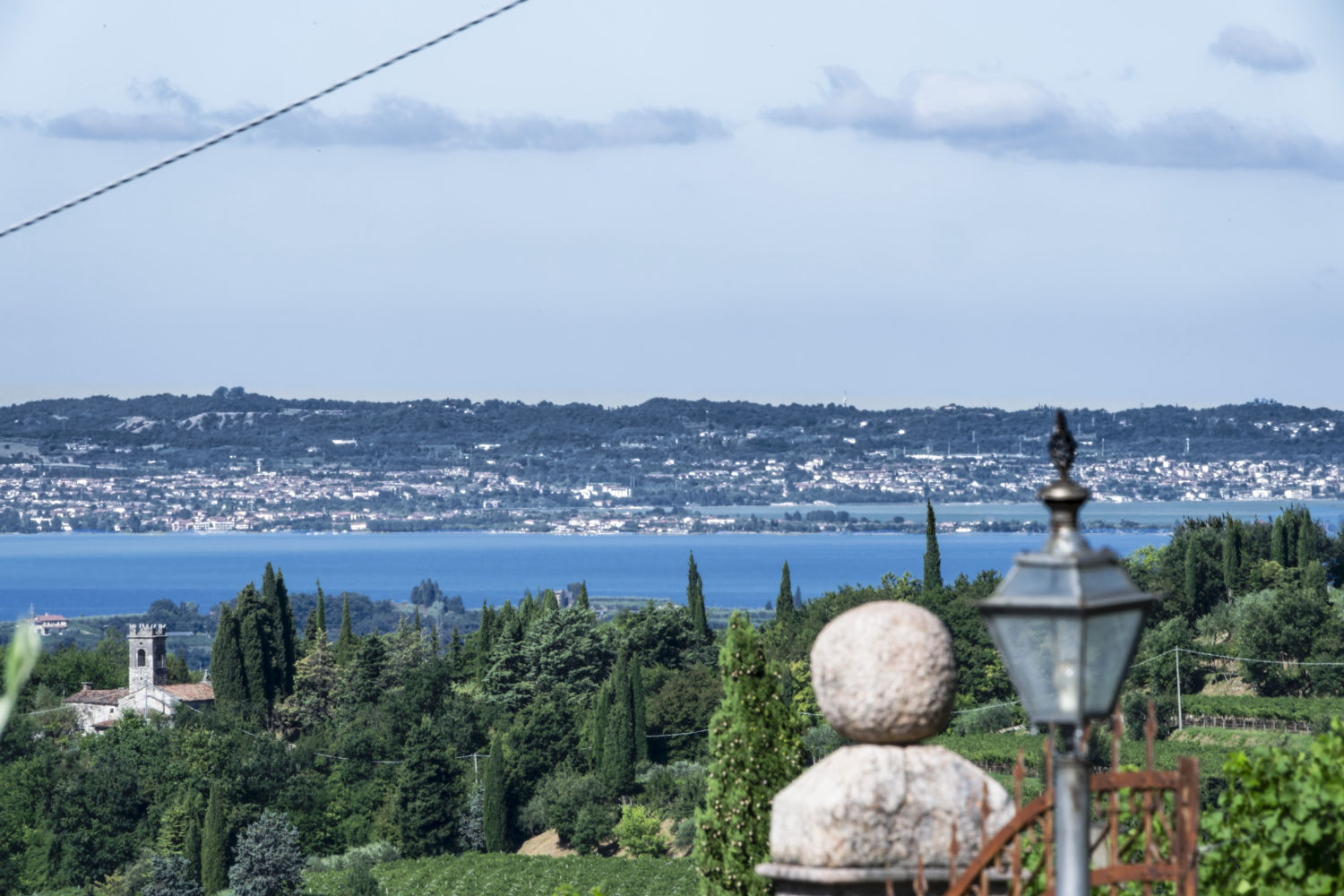 Blick auf die kleine Kirche San Zeno (unten links) und im Hintergrund die Halbinsel Sirmione und das Westufer (Brescia‑Seite) des Gardasees.